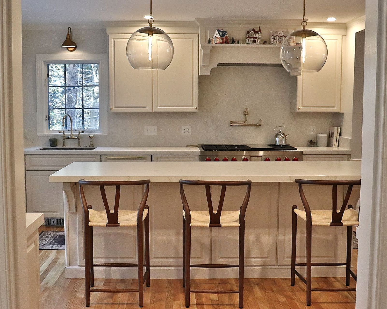 A kitchen with white cabinets and stools and a stove