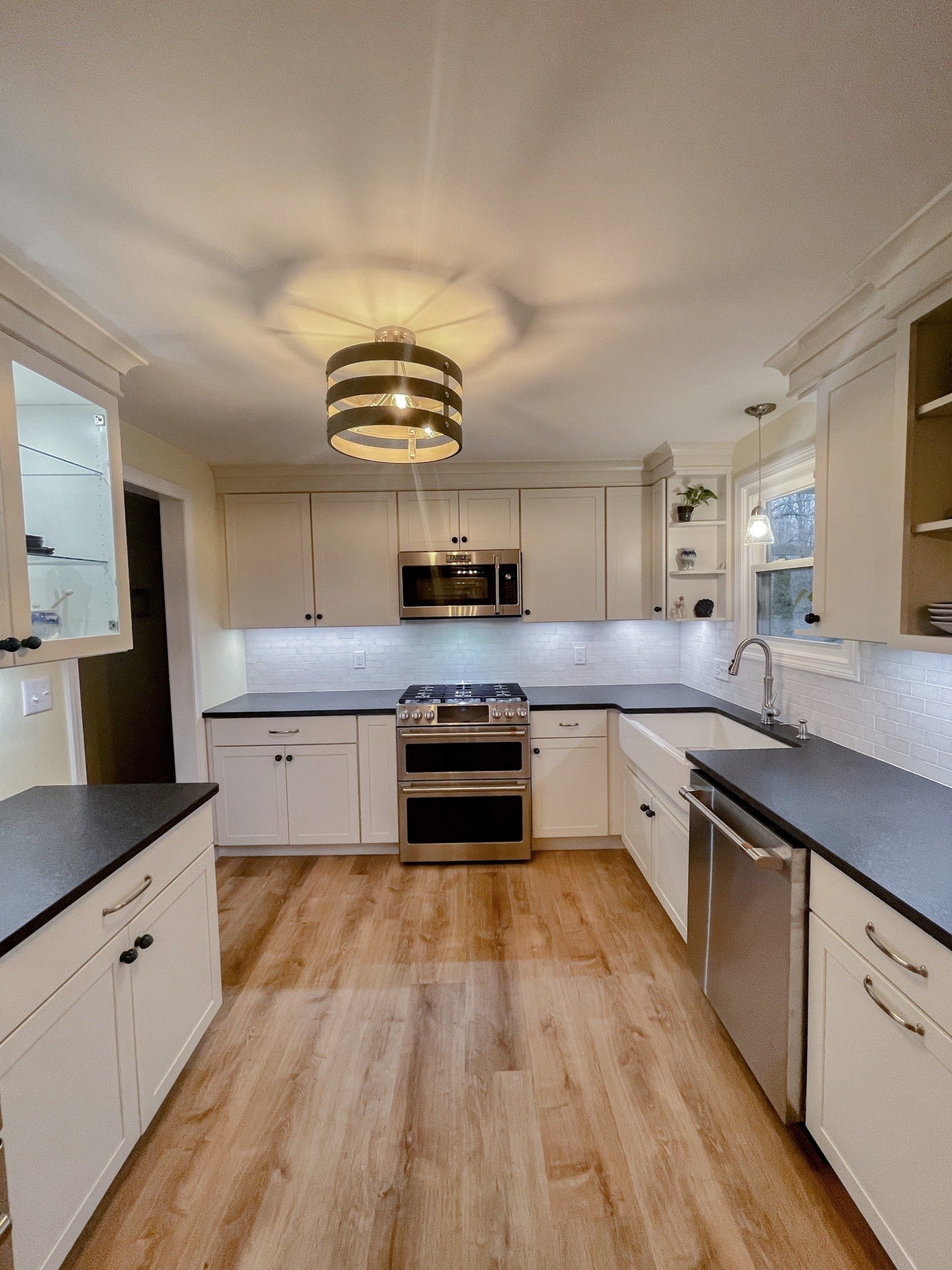 A kitchen with white cabinets , black counter tops , and stainless steel appliances.