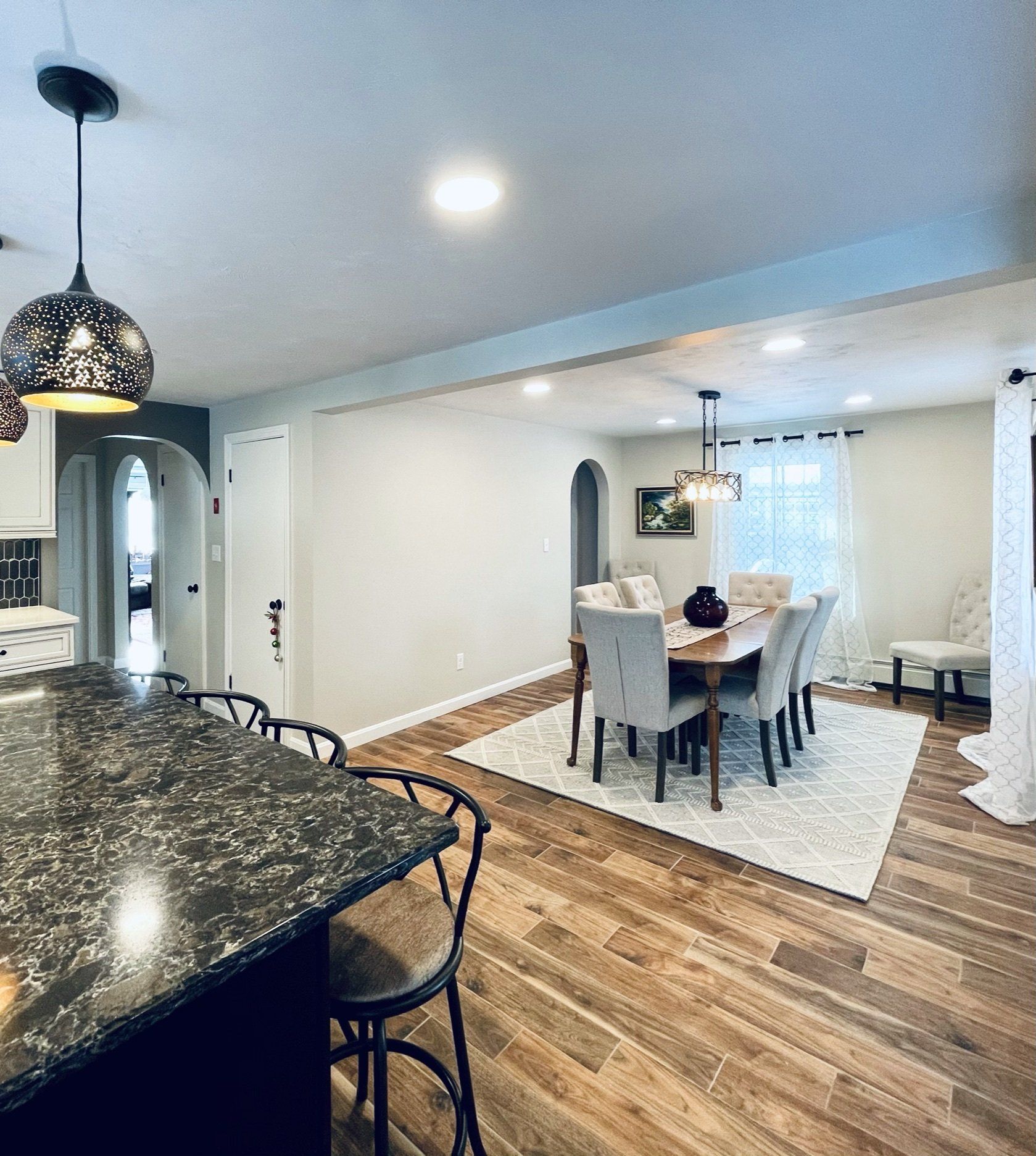 A dining room with a table and chairs and a rug on the floor.