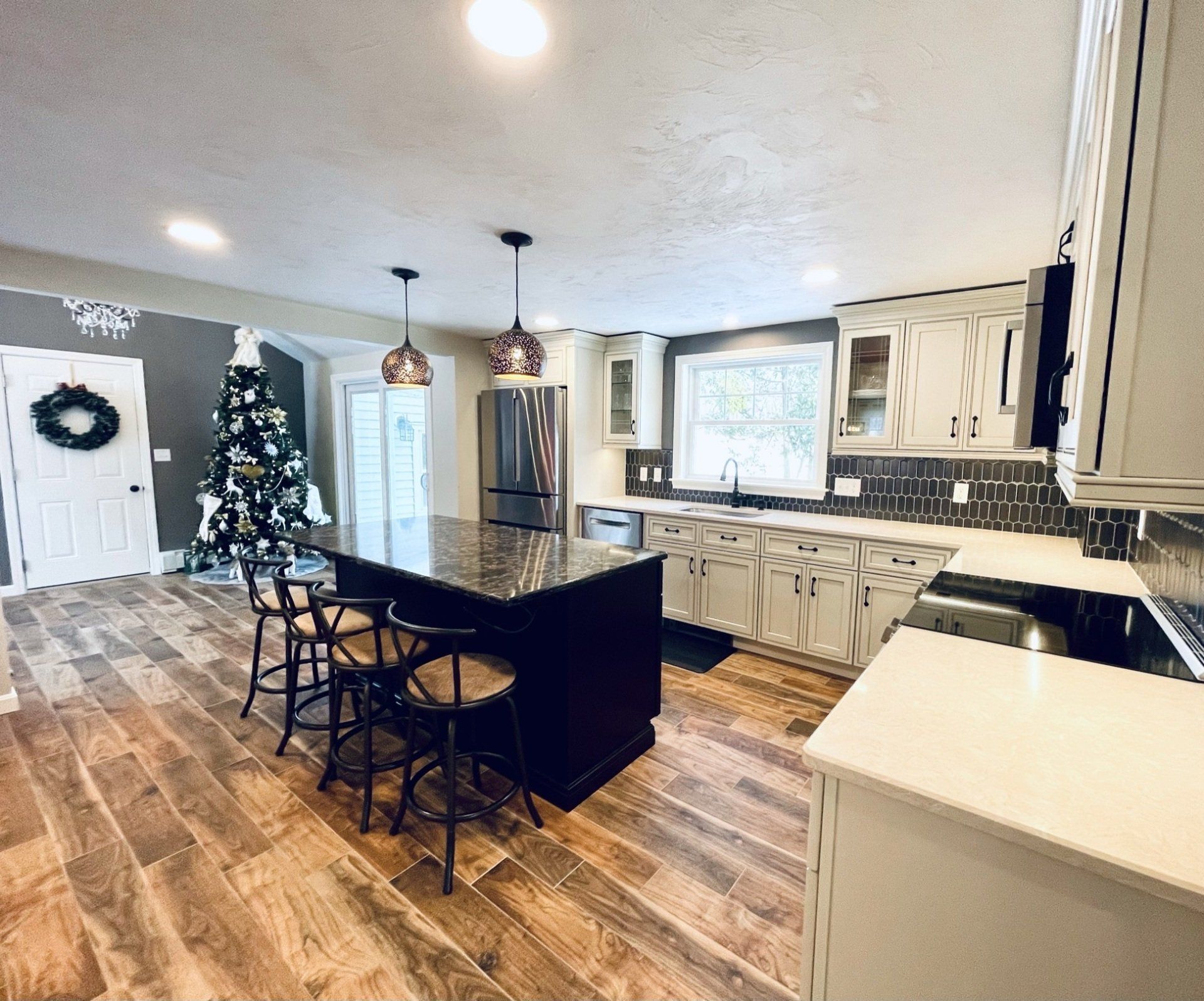 A kitchen with a large island and a christmas tree in the background.