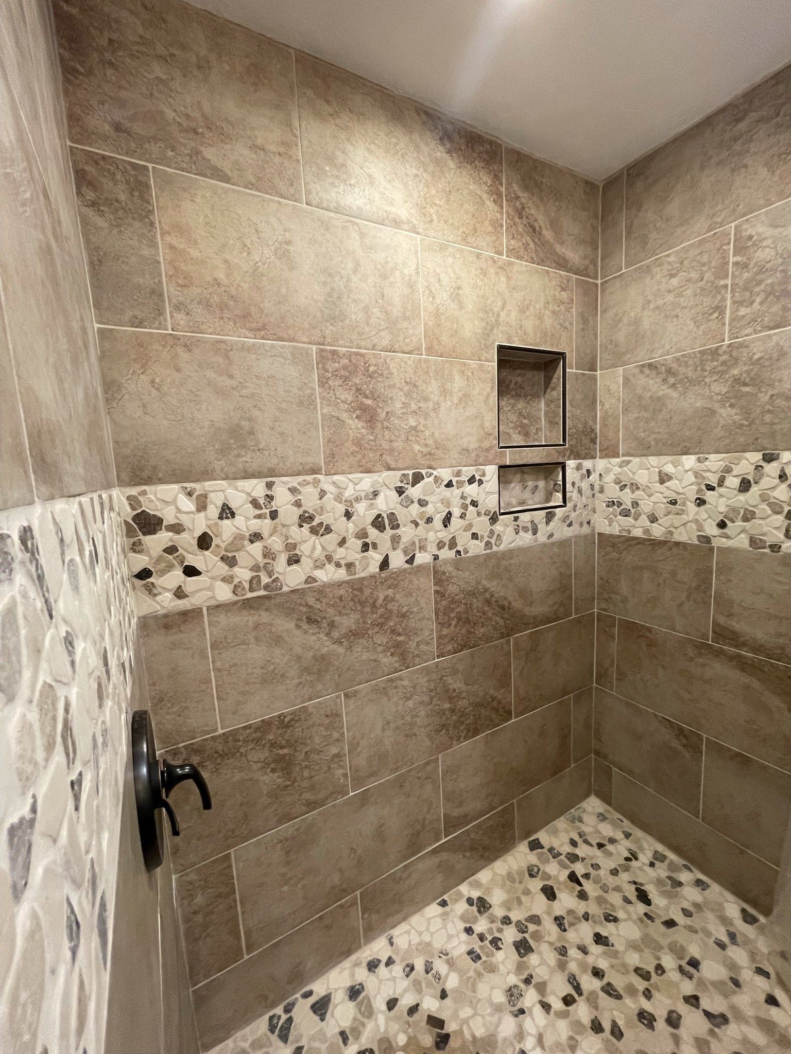 A walk in shower with tiled walls and a tiled floor.