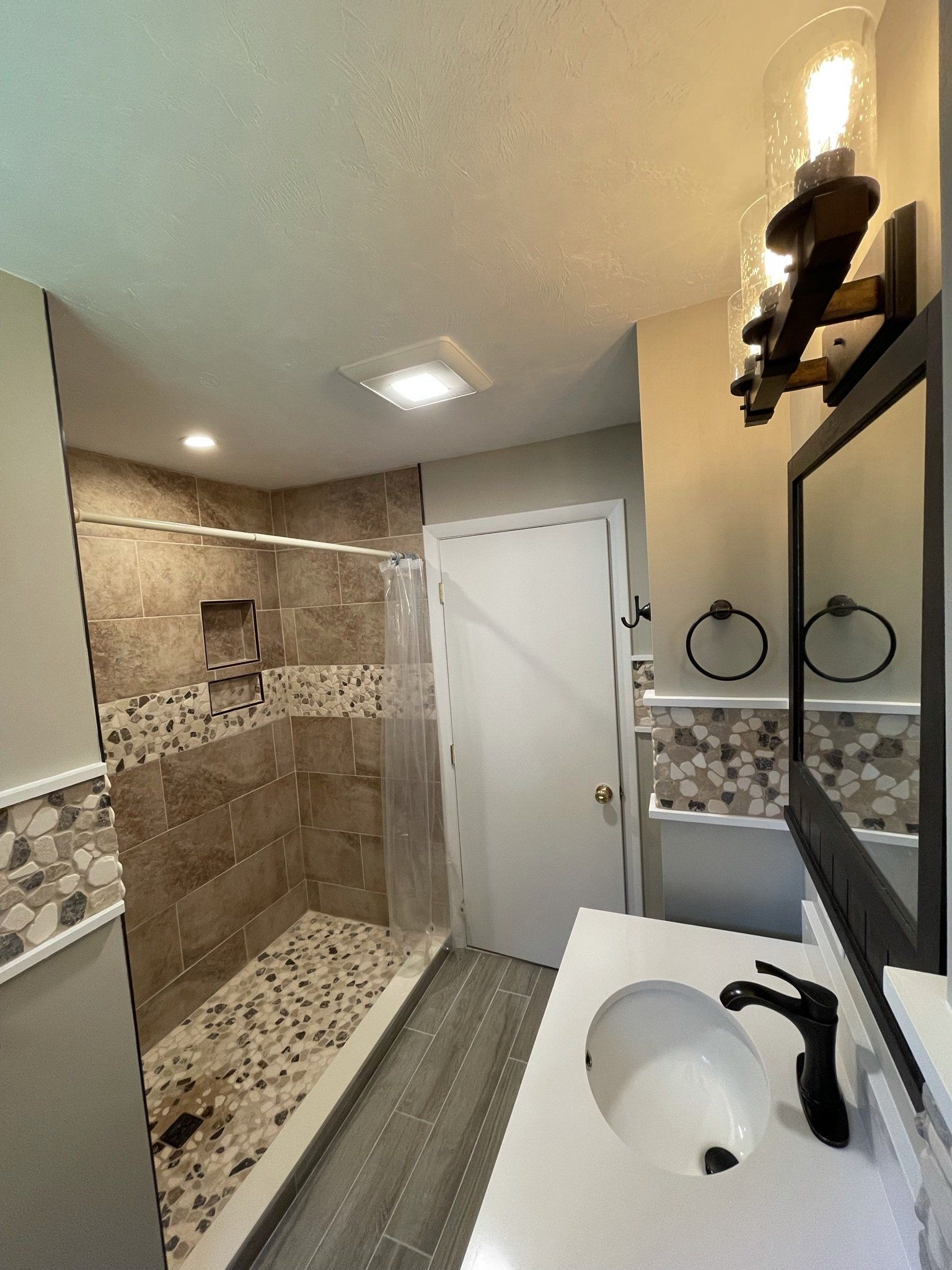 A bathroom with a sink , mirror and walk in shower.