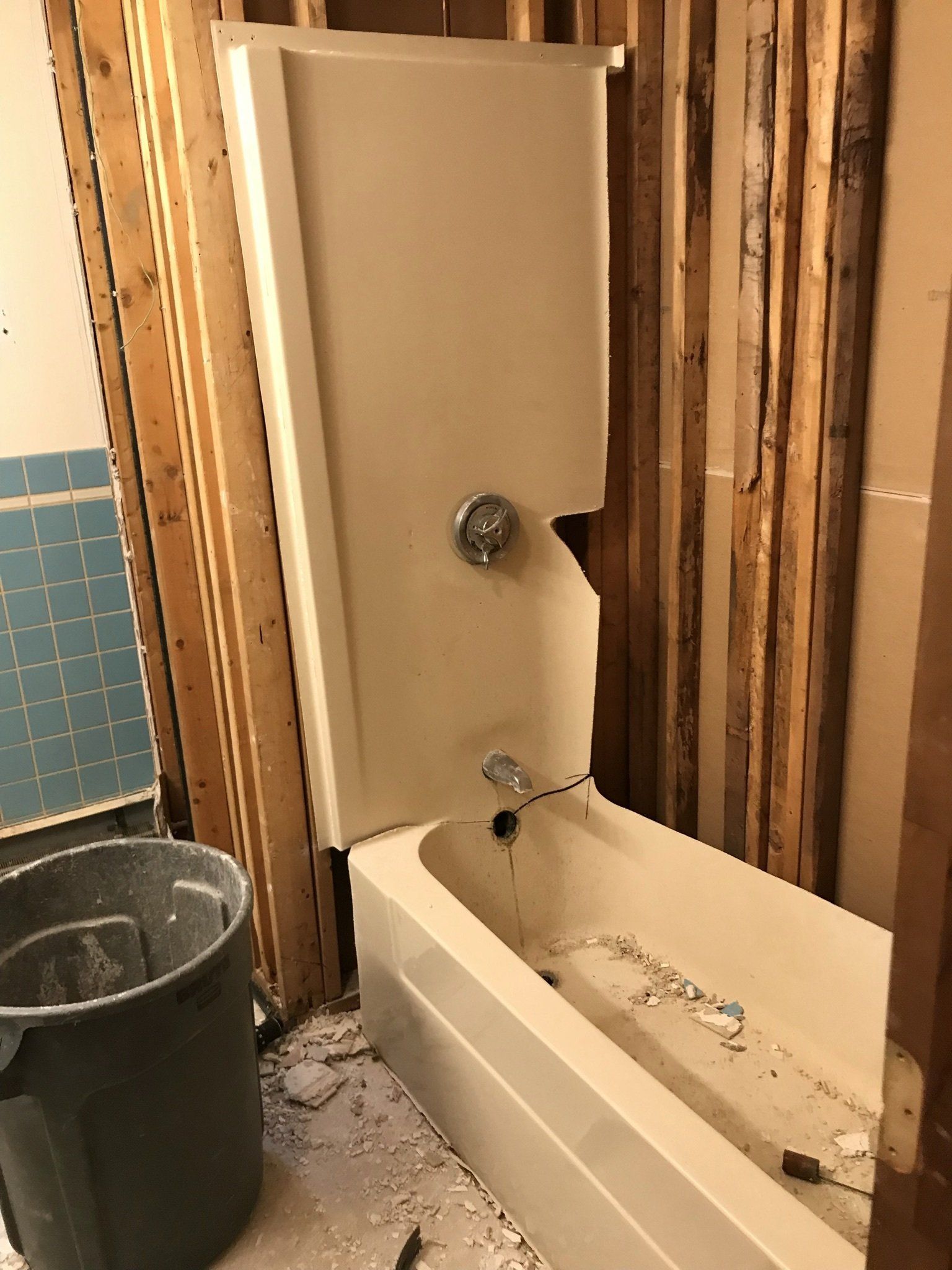 A bathtub is being remodeled in a bathroom with a bucket next to it.