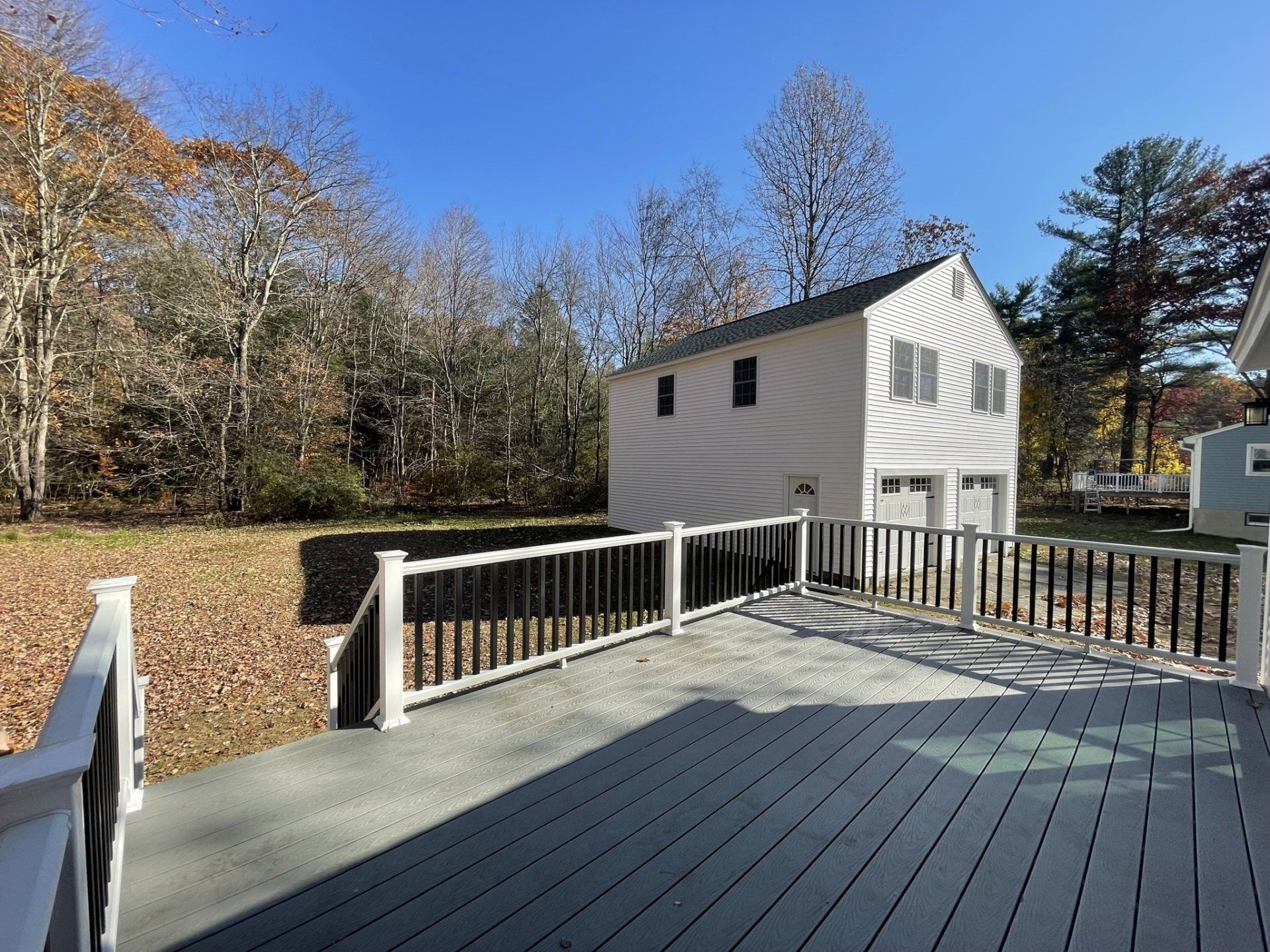 A deck with a white railing and a white house in the background