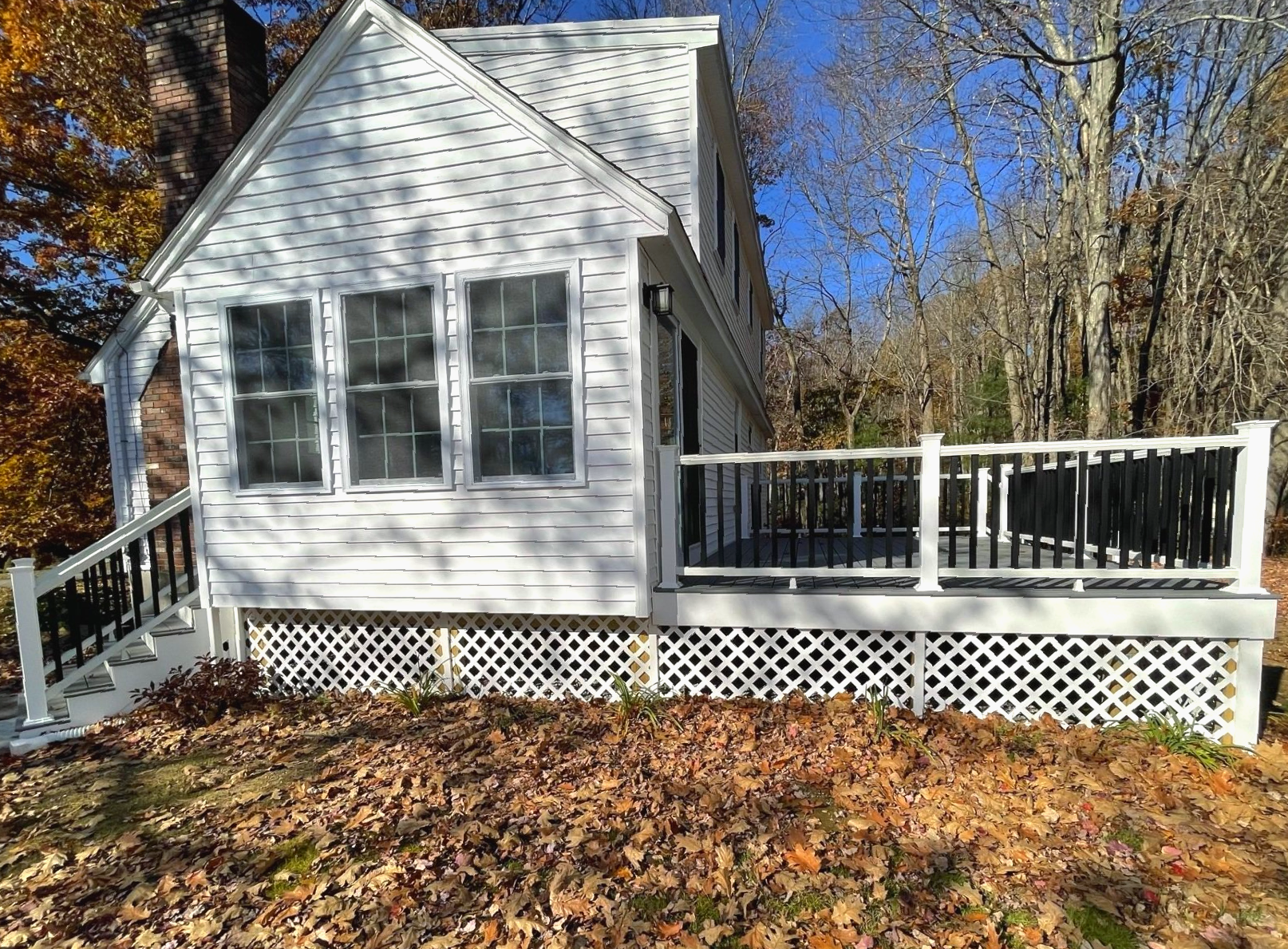 A small white house with a deck in the woods.
