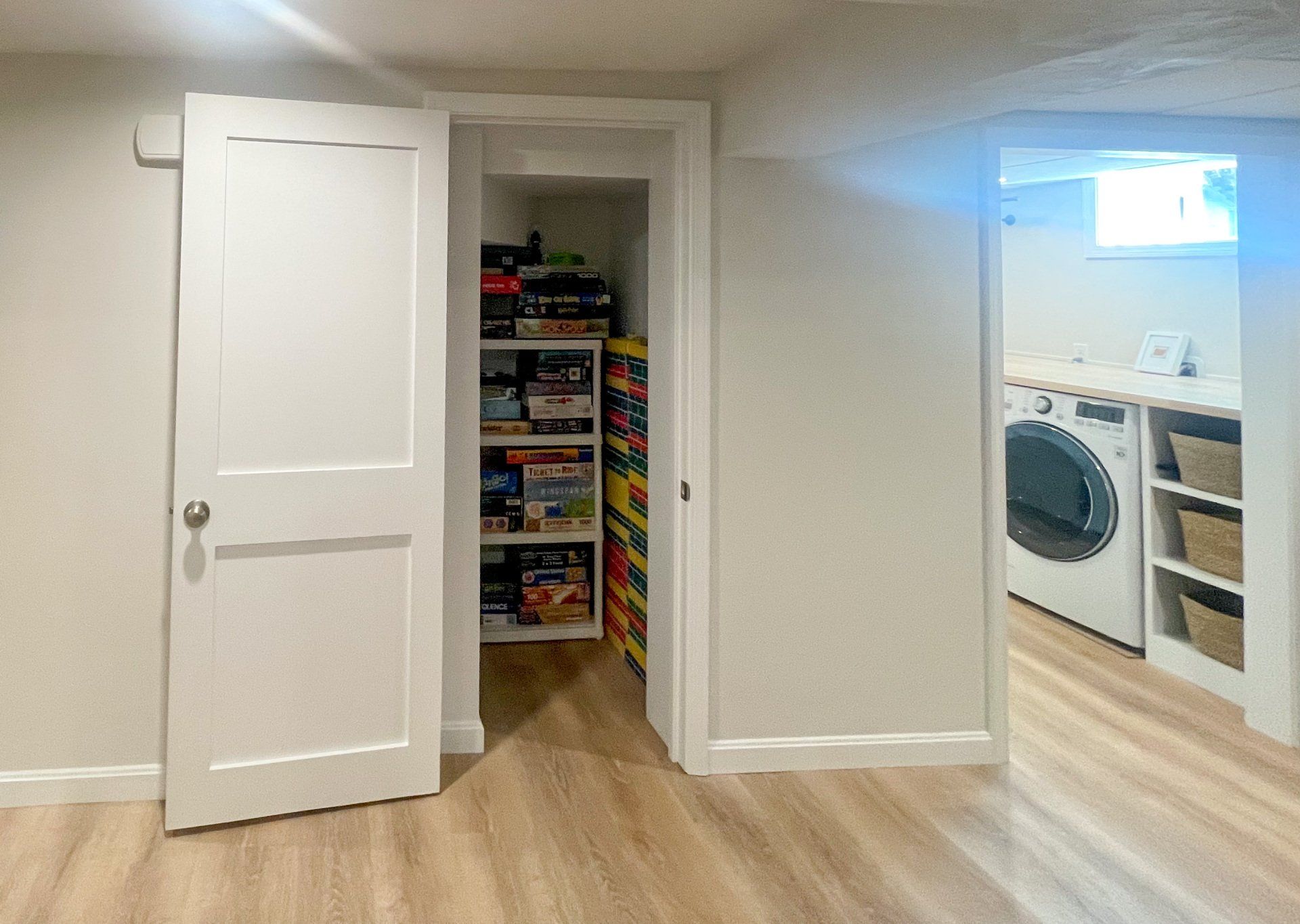 A laundry room with a washer and dryer and a closet filled with toys.
