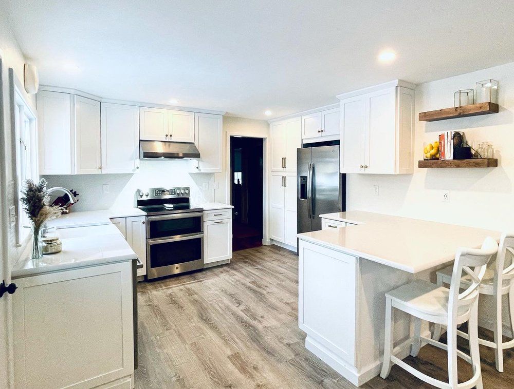 A kitchen with white cabinets , stainless steel appliances , and hardwood floors.