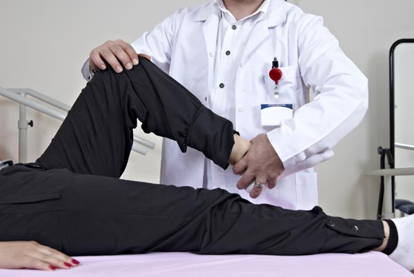 Physiotherapist giving a knee therapy to the male patient