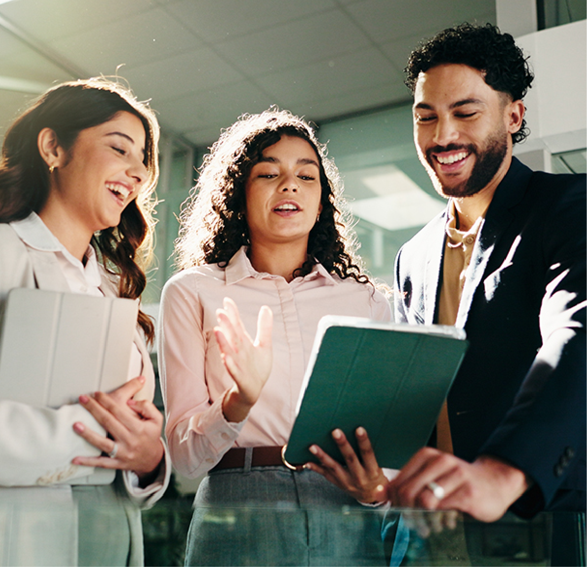 Three colleagues in business attire talk while looking at a green tablet inside a bright office.