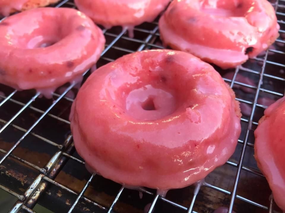 Pink-frosted donuts cooling on a wire rack