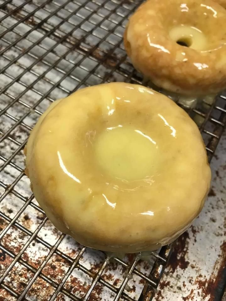 Two glazed donuts cooling on a wire rack, one large in front and one smaller behind.