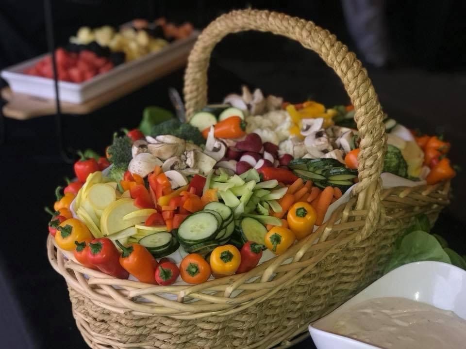Wicker basket filled with colorful fruit and vegetable skewers on a buffet table