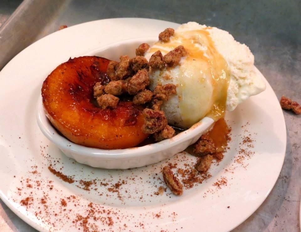 Caramelized fruit dessert with vanilla ice cream and crumb topping on a white plate