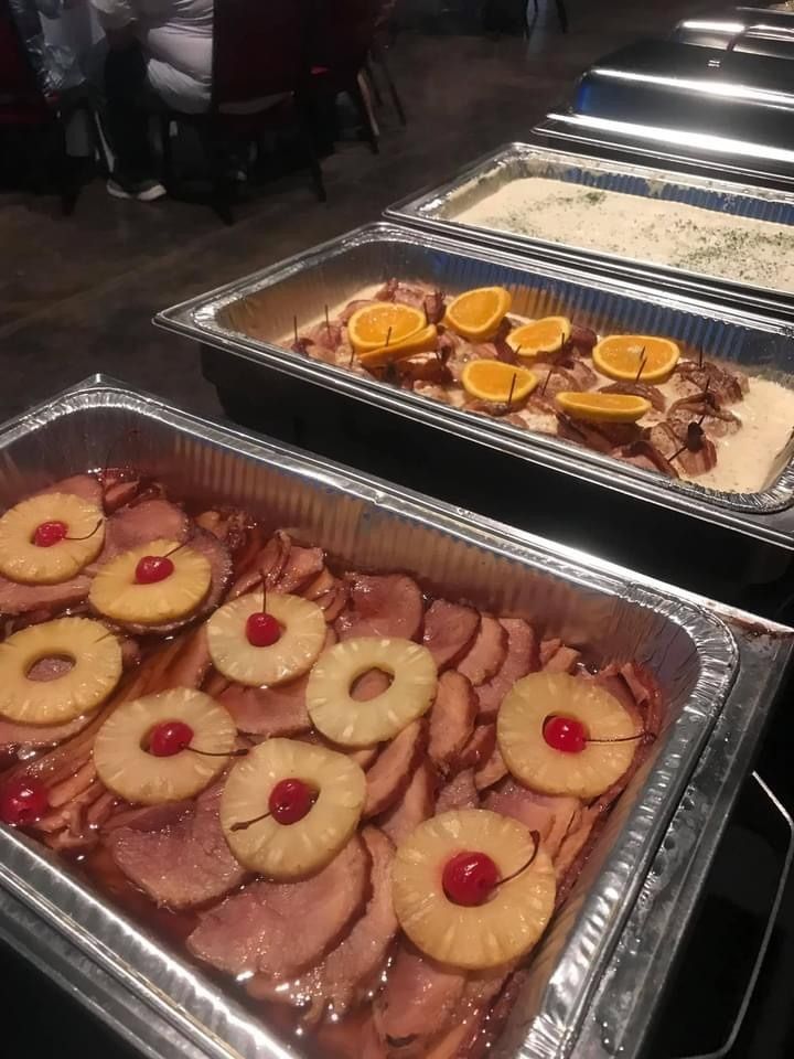 Two trays of assorted dessert squares and tarts topped with pineapple and cherries at a buffet