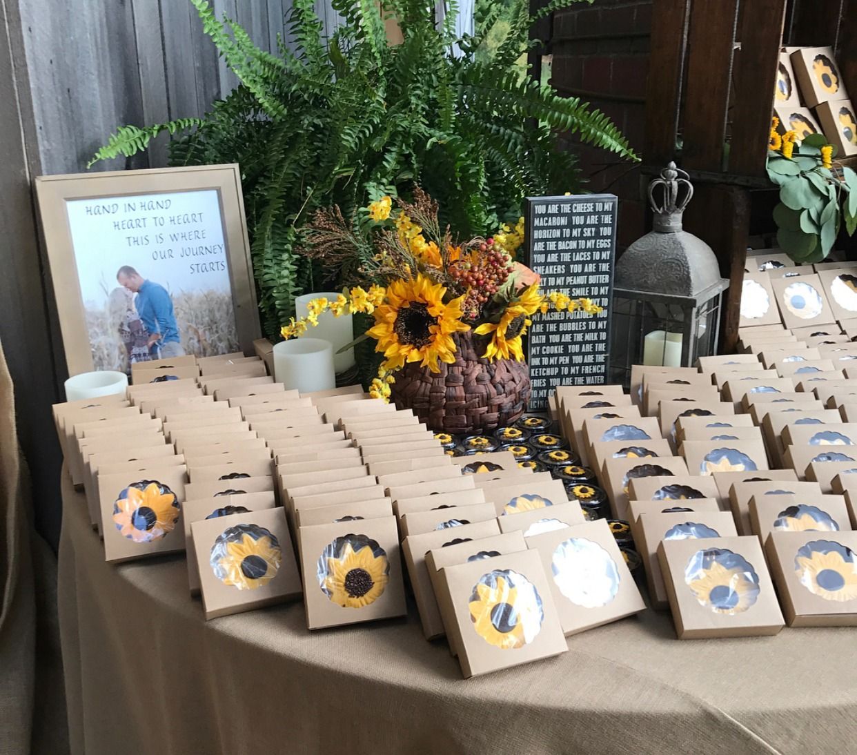 Table of packaged treats with sunflower labels and floral decor at a rustic display
