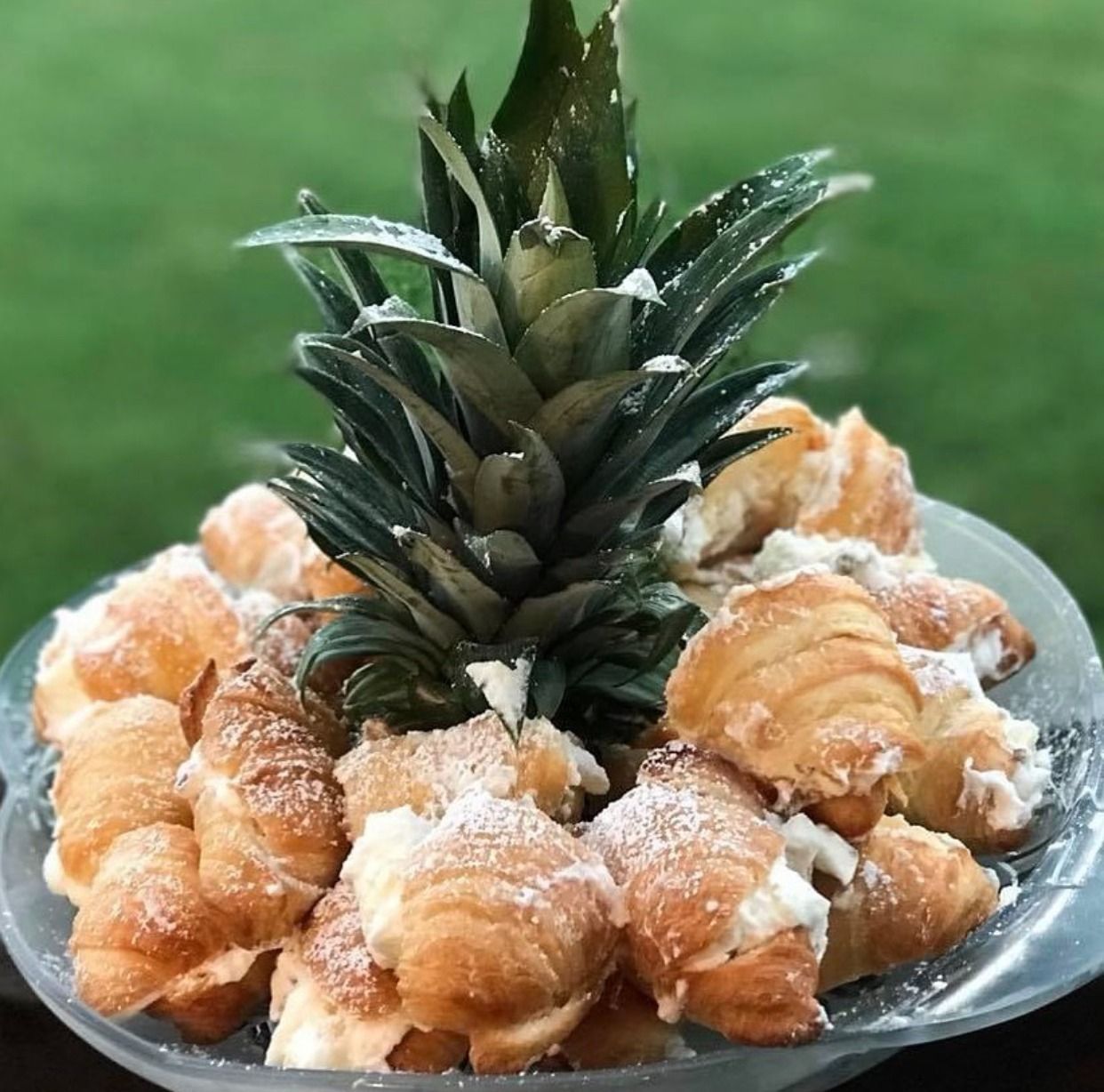 Pineapple topped with powdered pastries on a glass plate