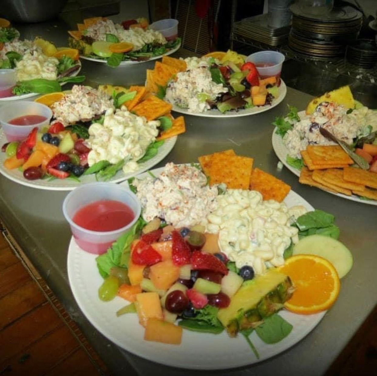 Plates of colorful fruit and salad buffet with red drinks on a table