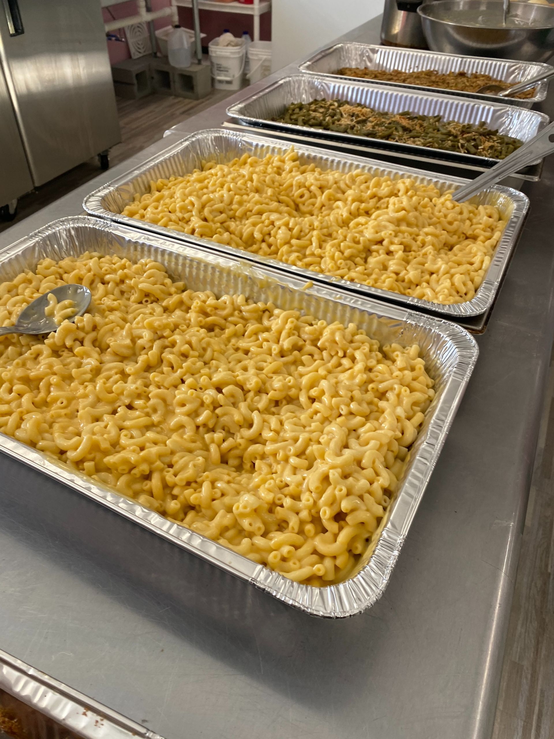 Tray of macaroni and cheese at a buffet, with more pans of pasta behind it