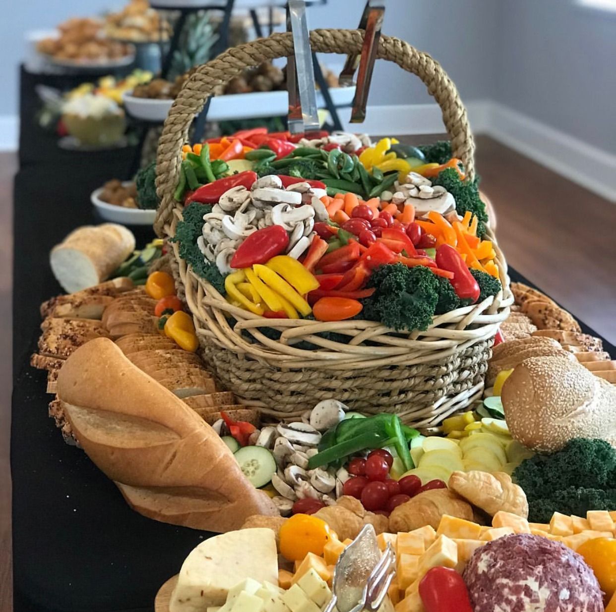 Wicker basket of assorted colorful vegetables on a table with bread and cheese in the foreground