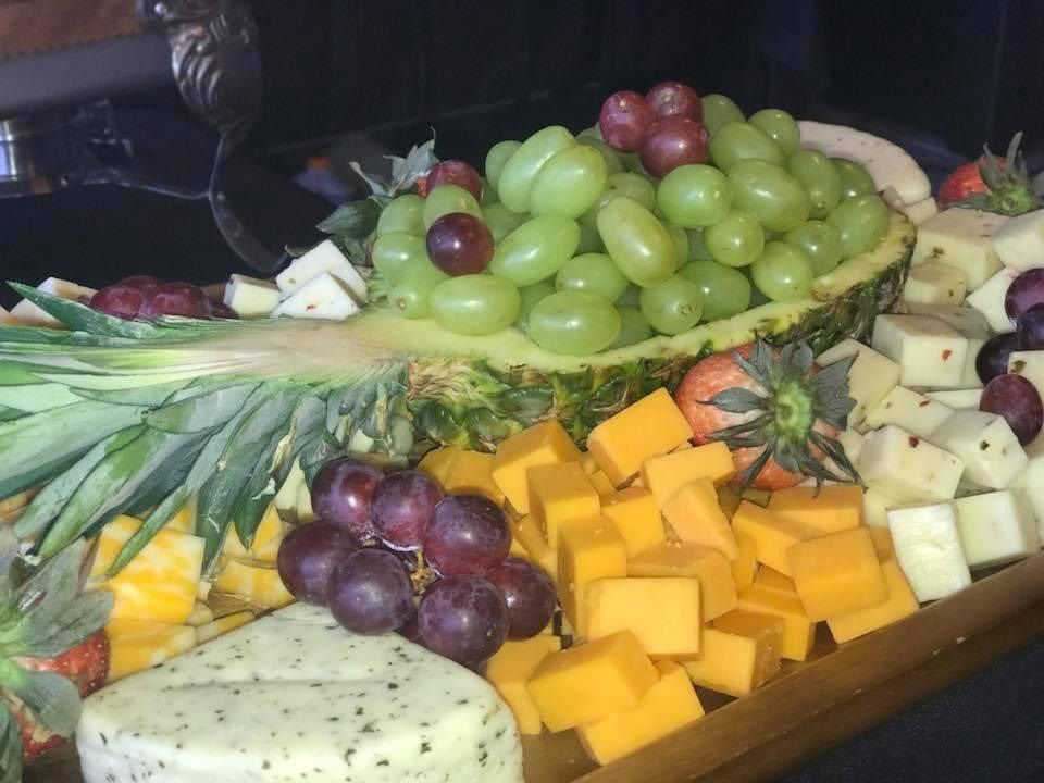 Fruit and cheese platter with grapes, pineapple, mango, and cubed cheese on a tray