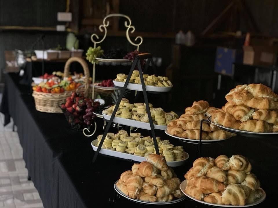Tiered trays of pastries and fruit on a black tablecloth in a dim room
