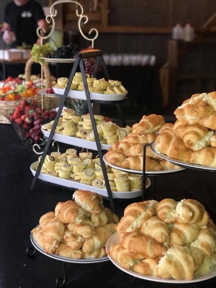 Tiered trays of croissants and pastries on a buffet table in a warmly lit café.