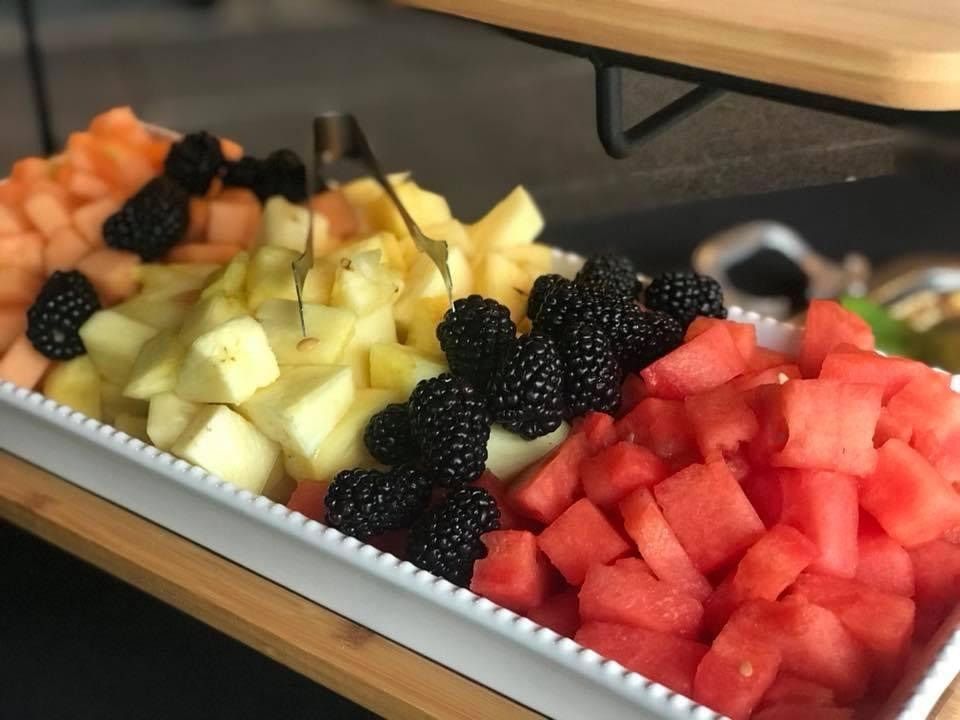 Tray of assorted cubed fruit, including watermelon, pineapple, and blackberries, on a buffet table