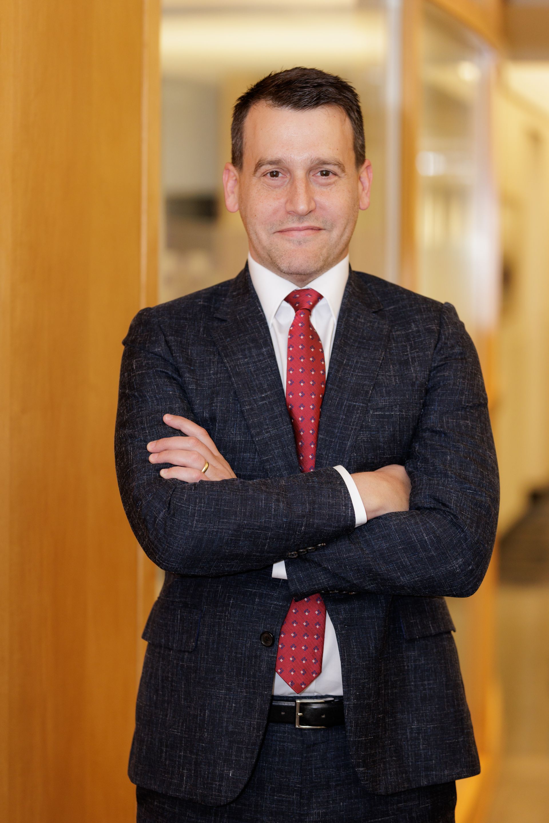 A man in a suit and tie is standing with his arms crossed.