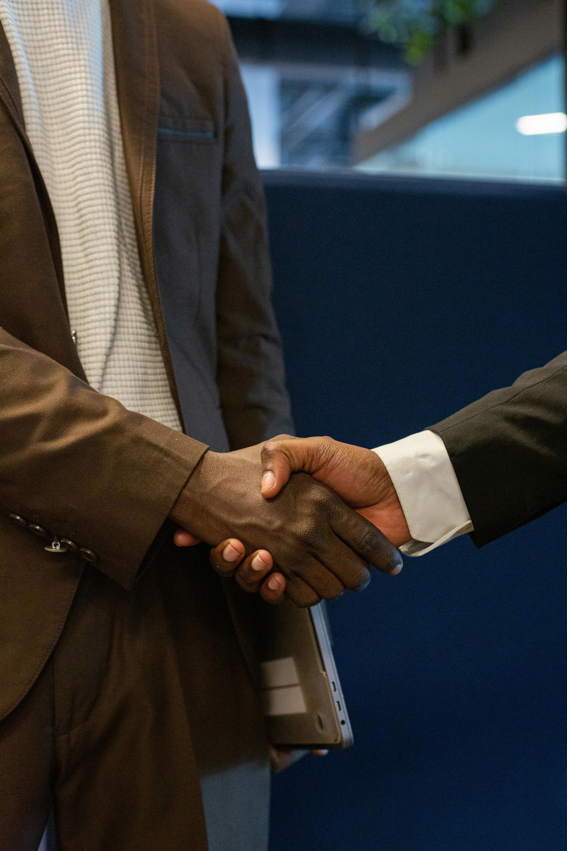 A man in a suit and tie is shaking hands with another man.