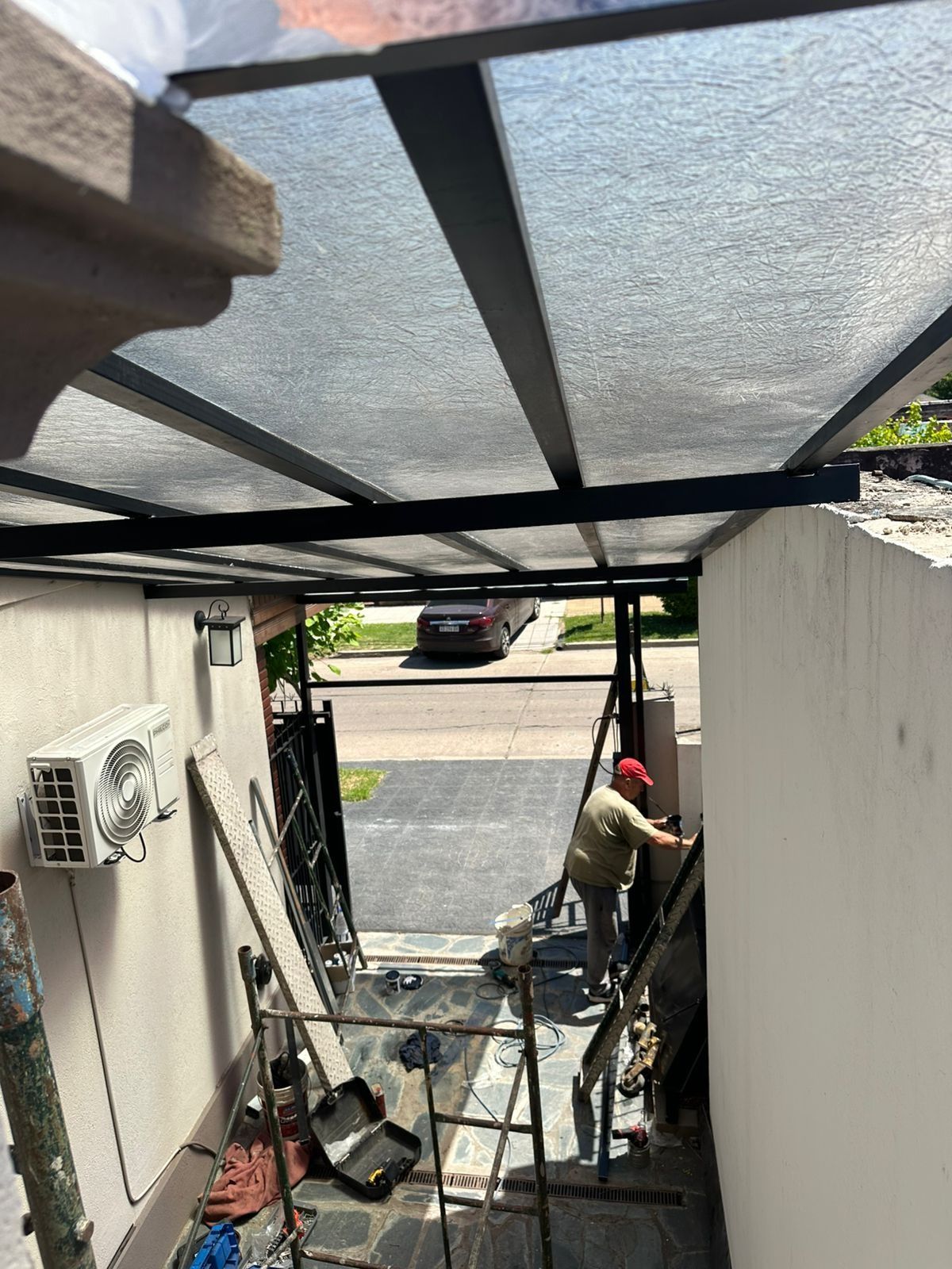 Escalera exterior cubierta con un trabajador usando herramientas junto a una casa