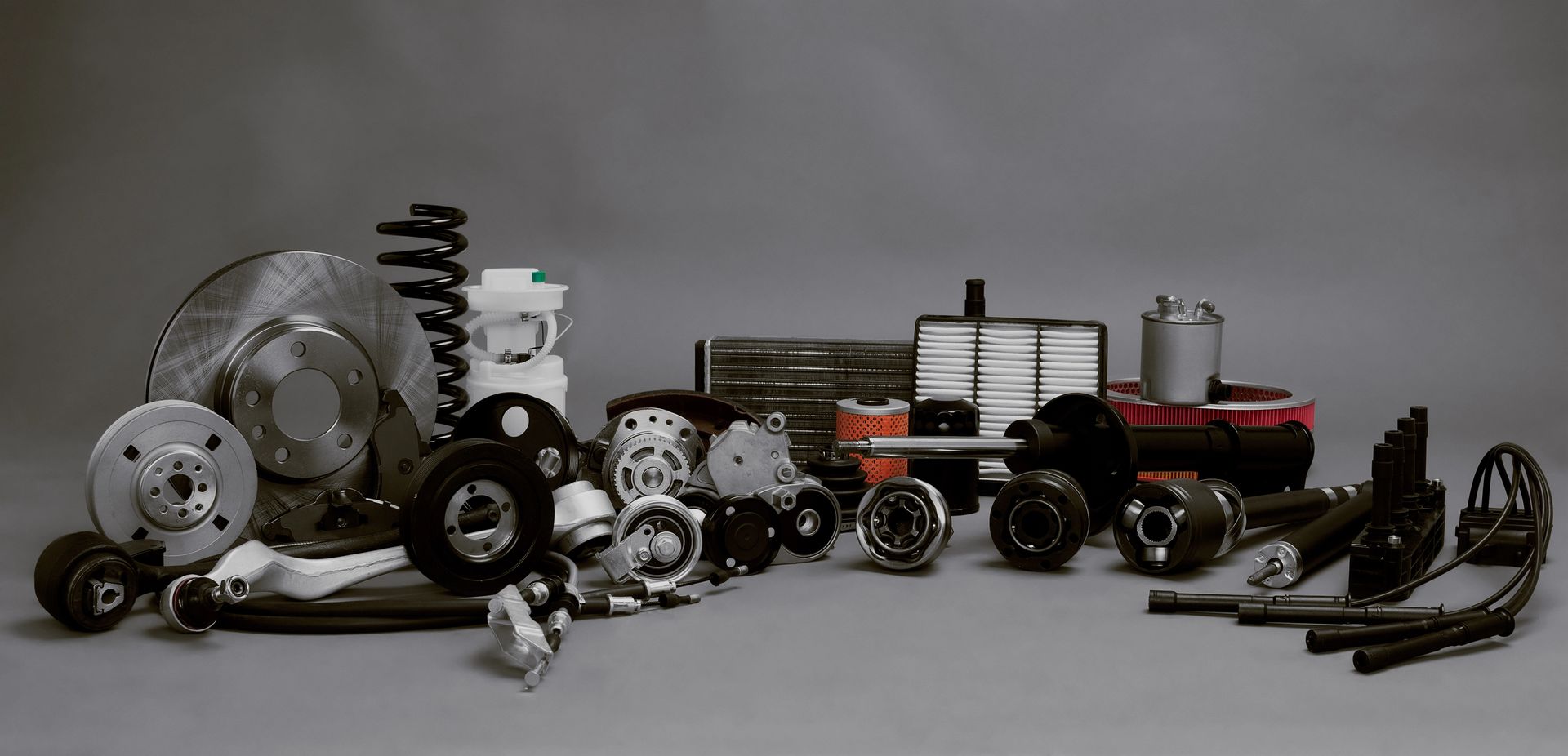 Surtido de piezas de automóvil sobre fondo gris.