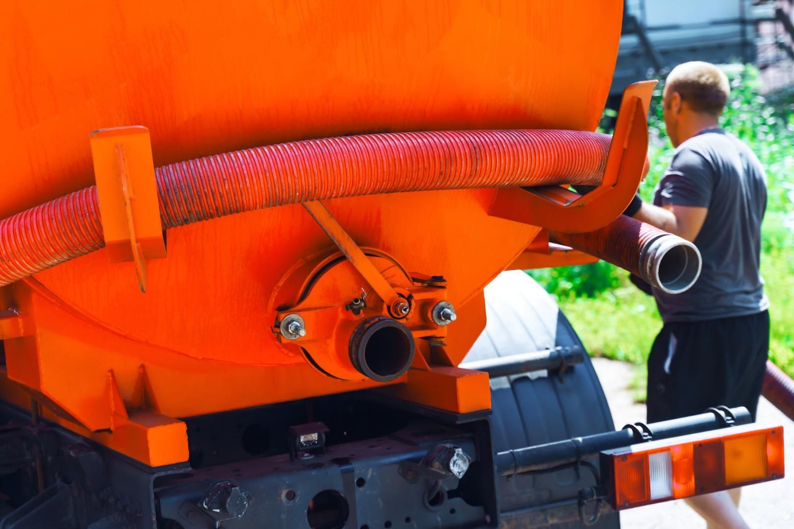 Man is Holding a Hose Next to an Orange Truck — Precious Drop Water in Piggabeen, NSW