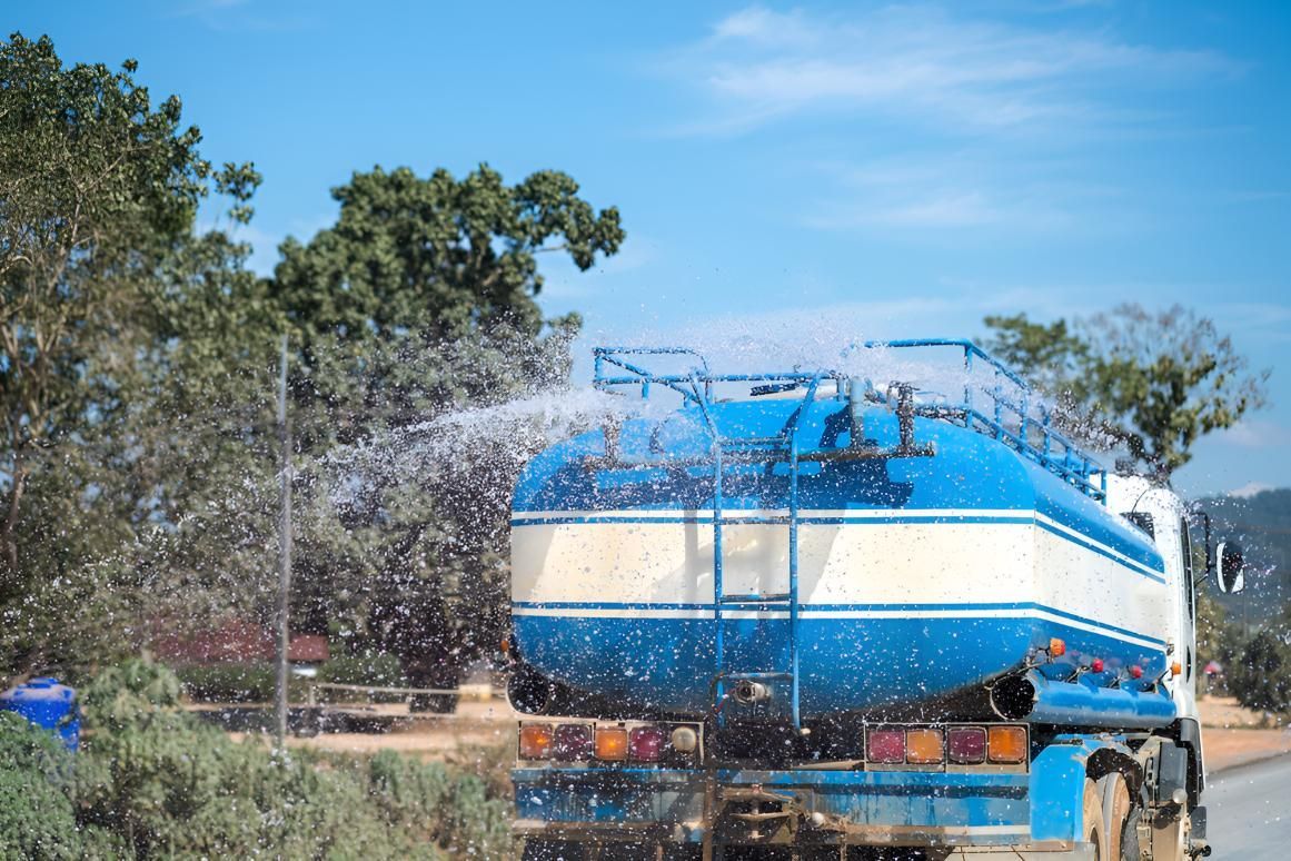 Blue and White Water Truck is Spraying Water — Precious Drop Water in Stokers Siding, NSW