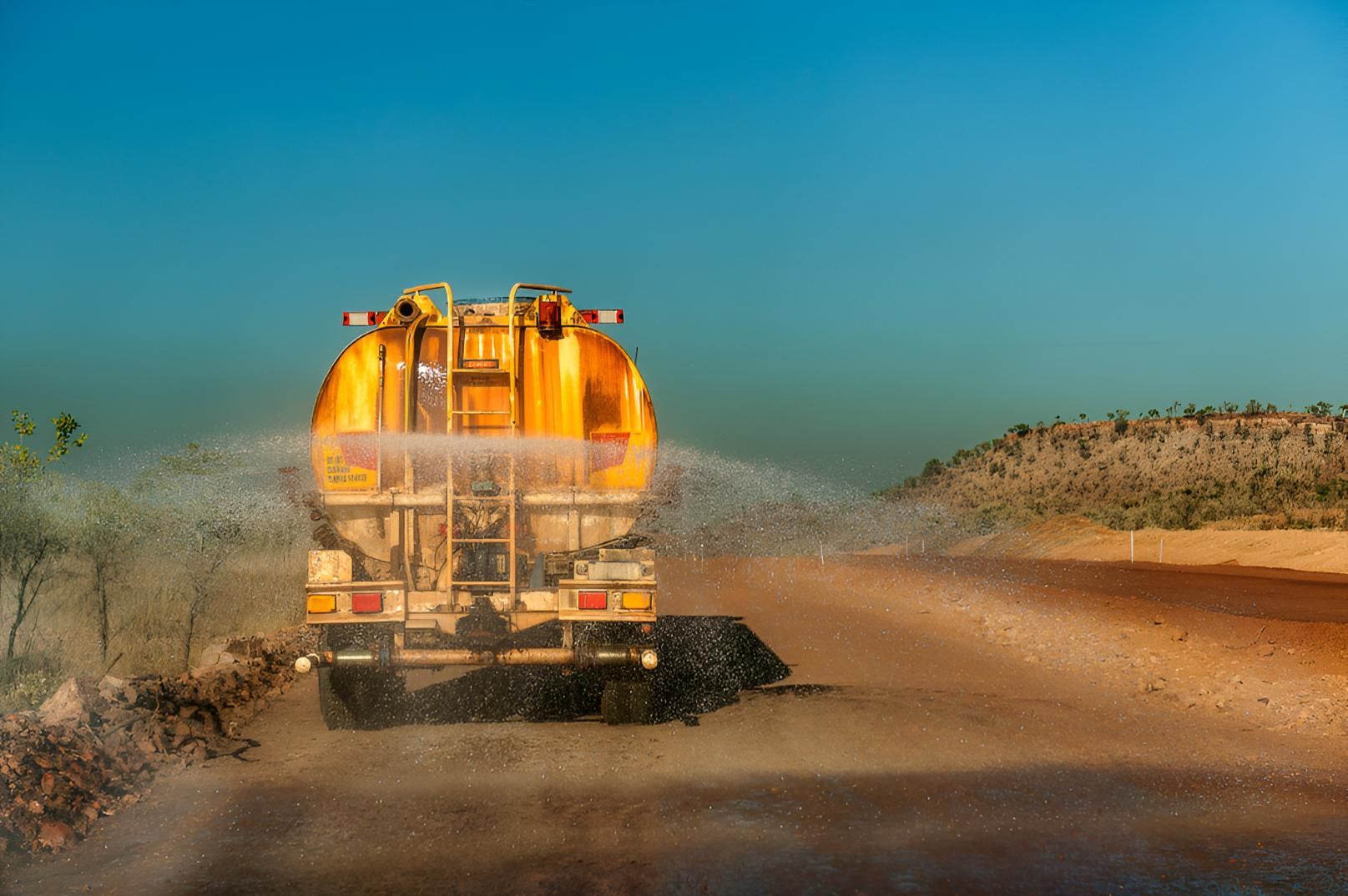 Yellow Truck is Spraying Water on a Dirt Road — Precious Drop Water in Murwillumbah, NSW