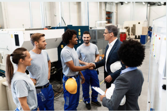 A group of people are shaking hands in a factory.