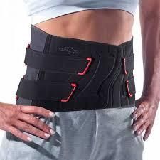 Persona que lleva un corsé ortopédico negro con correas rojas sobre una camisa y pantalones grises.