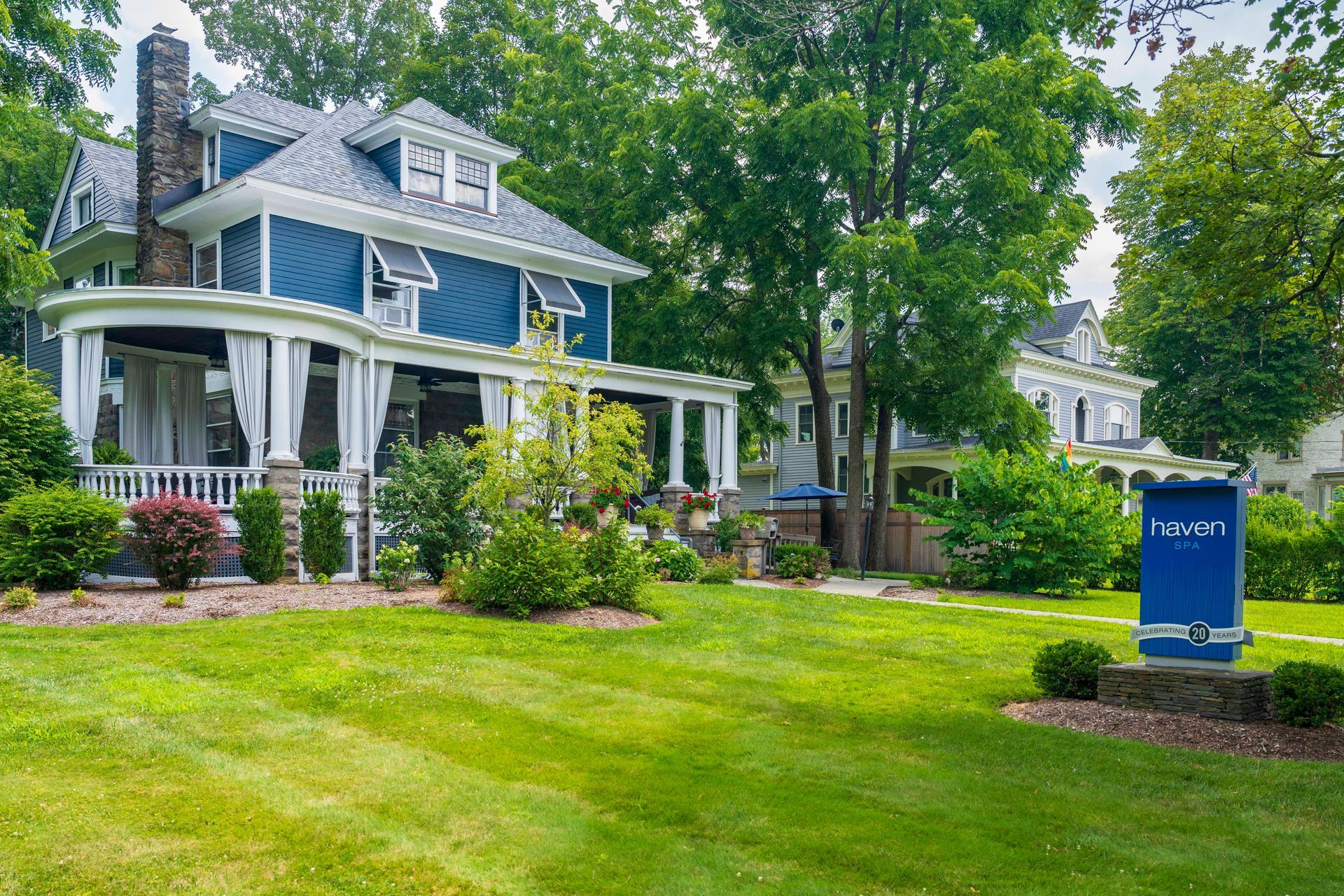 Blue house with porch and yard, sign in front.