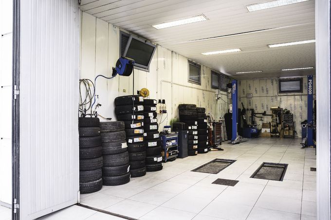 Un'officina di riparazione auto ben illuminata, con pneumatici accatastati e attrezzature.