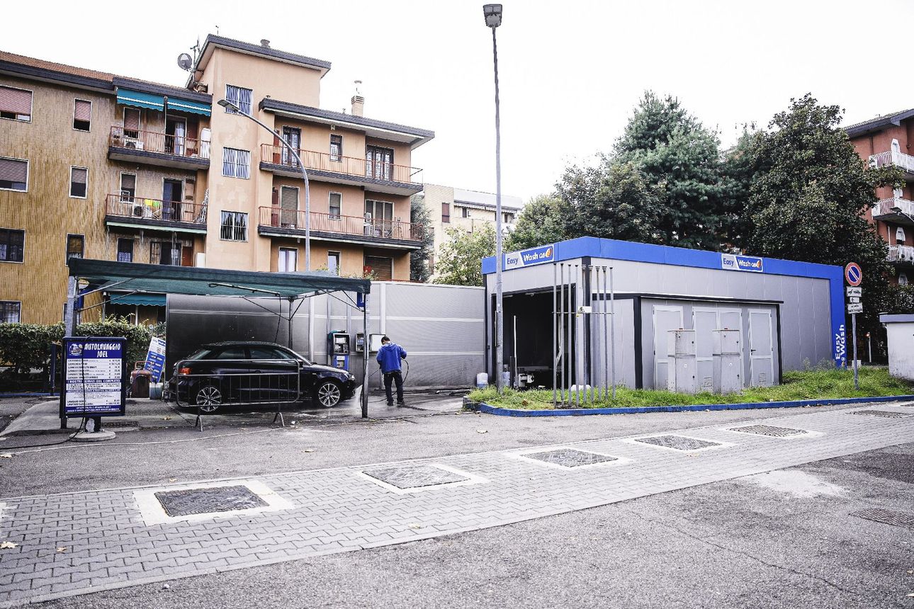 Autolavaggio Joel con un'auto nera, edifici e una persona a Milano