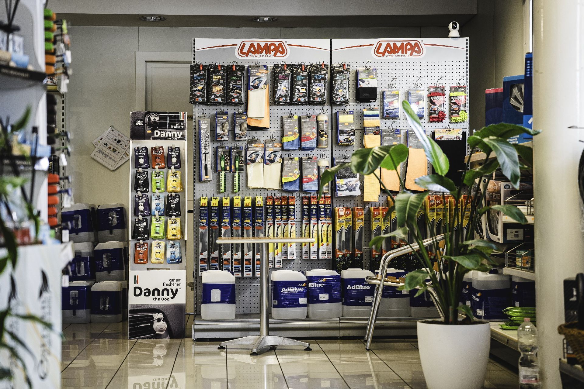 Interno di un negozio Svolta Q8 che espone prodotti per la pulizia dell'auto. I prodotti sono appesi su bacheche e accanto c'è una pianta in vaso.