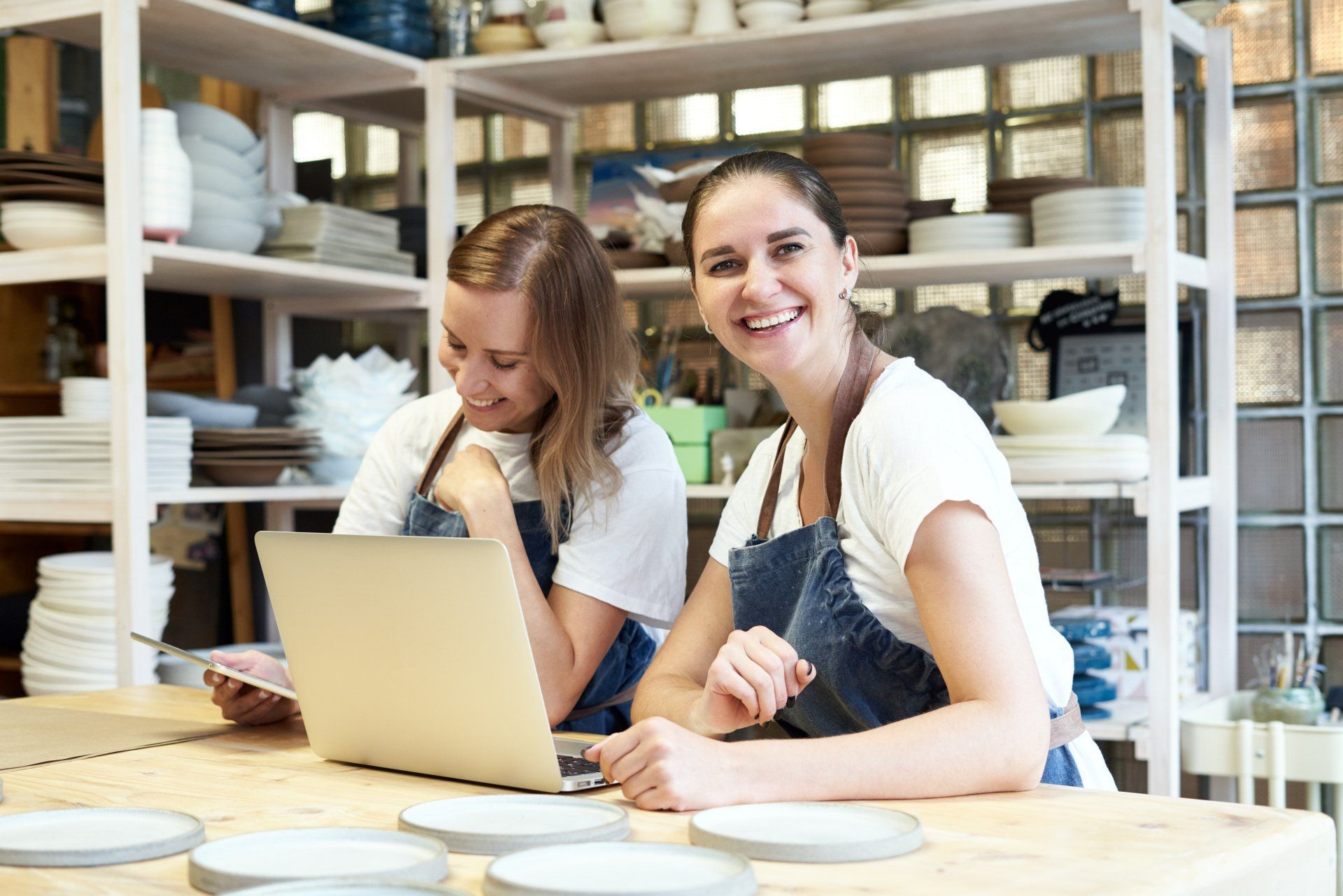 Dos empresaria sonriente con portátil en el taller artesanal