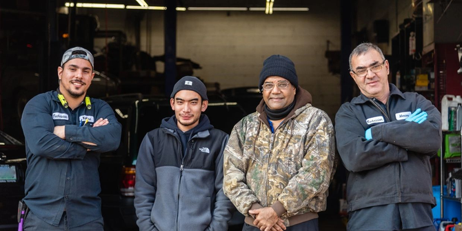 A group of men are posing for a picture in a garage. | Van Dorn Auto Repair