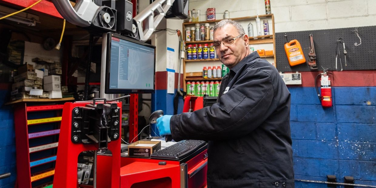 A man is working on a computer in a garage. | Van Dorn Auto Repair