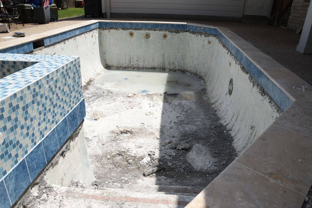 Empty drained swimming pool with cracked white walls and blue tile edging