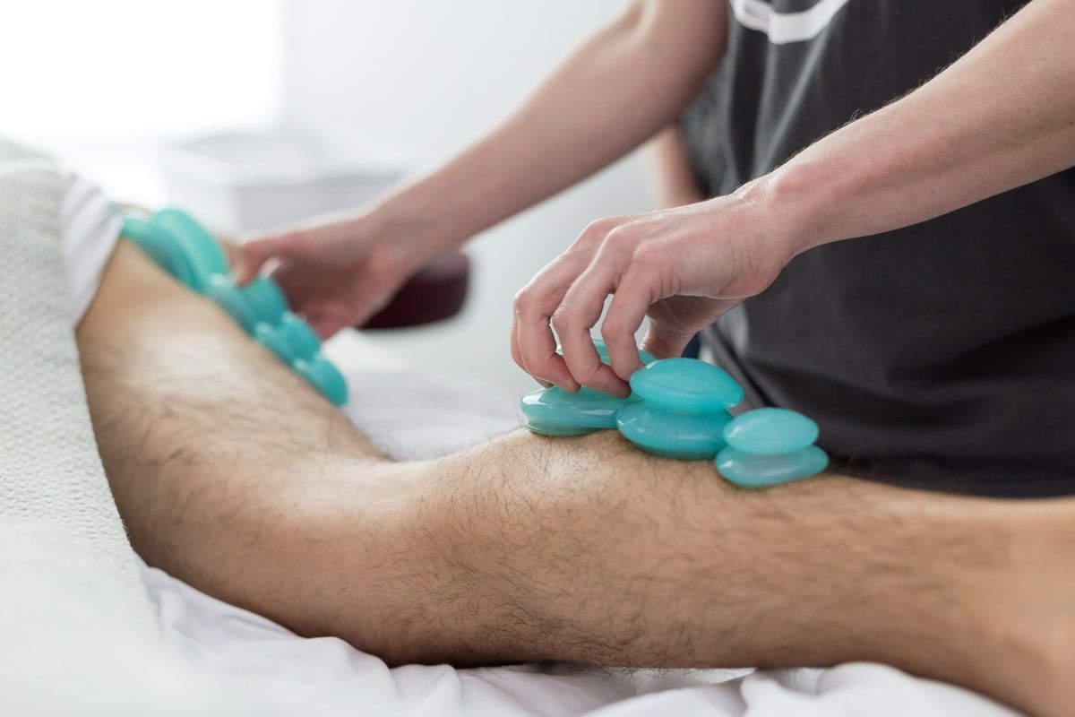 A man is getting a massage with blue cups on his leg.