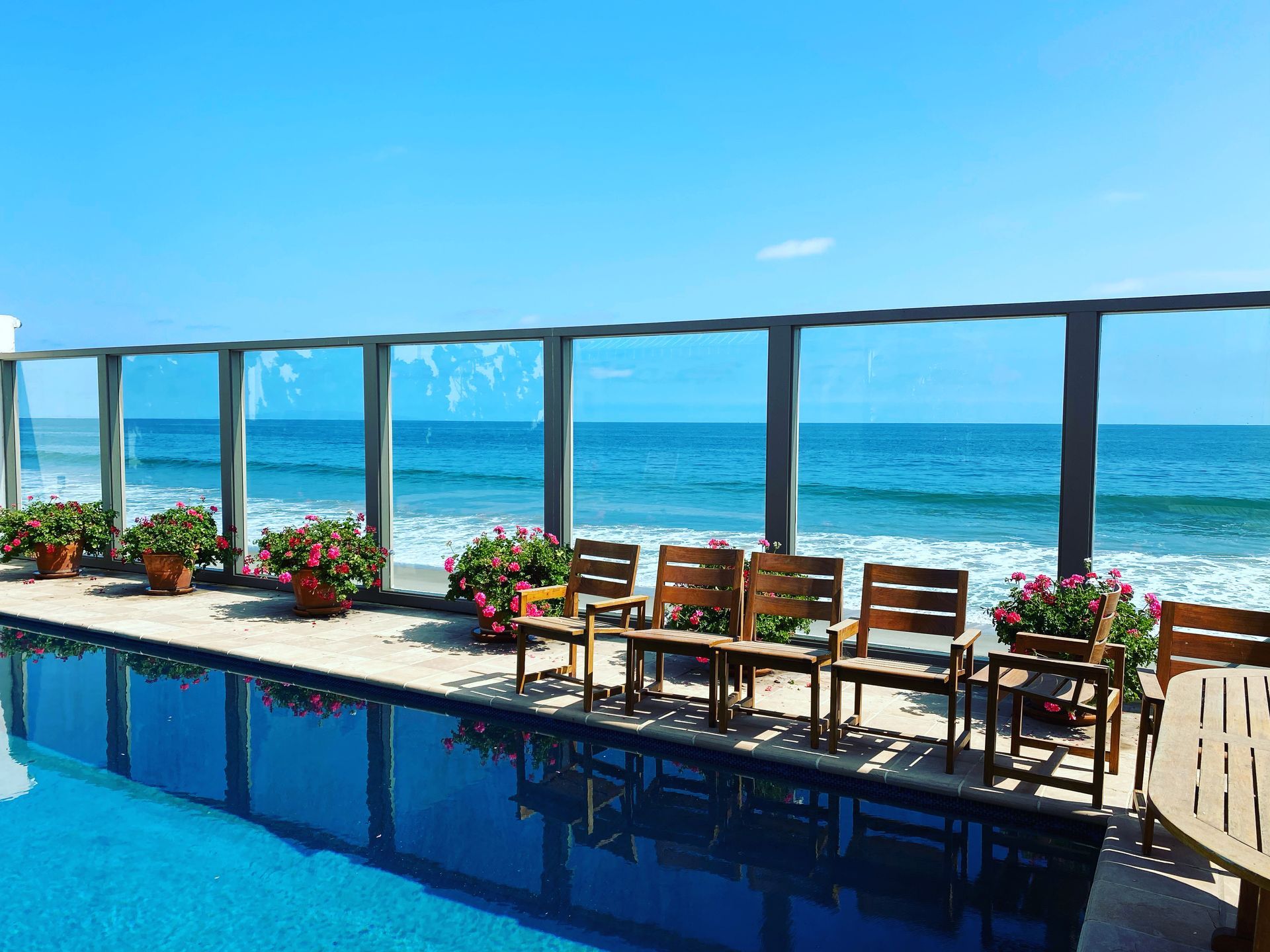 a swimming pool surrounded by chairs and tables overlooking the ocean