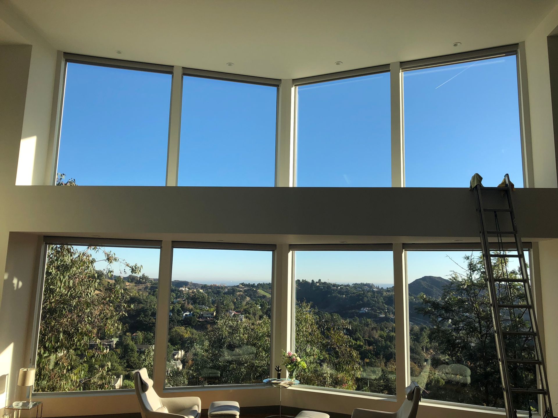 a living room with a lot of windows and a ladder