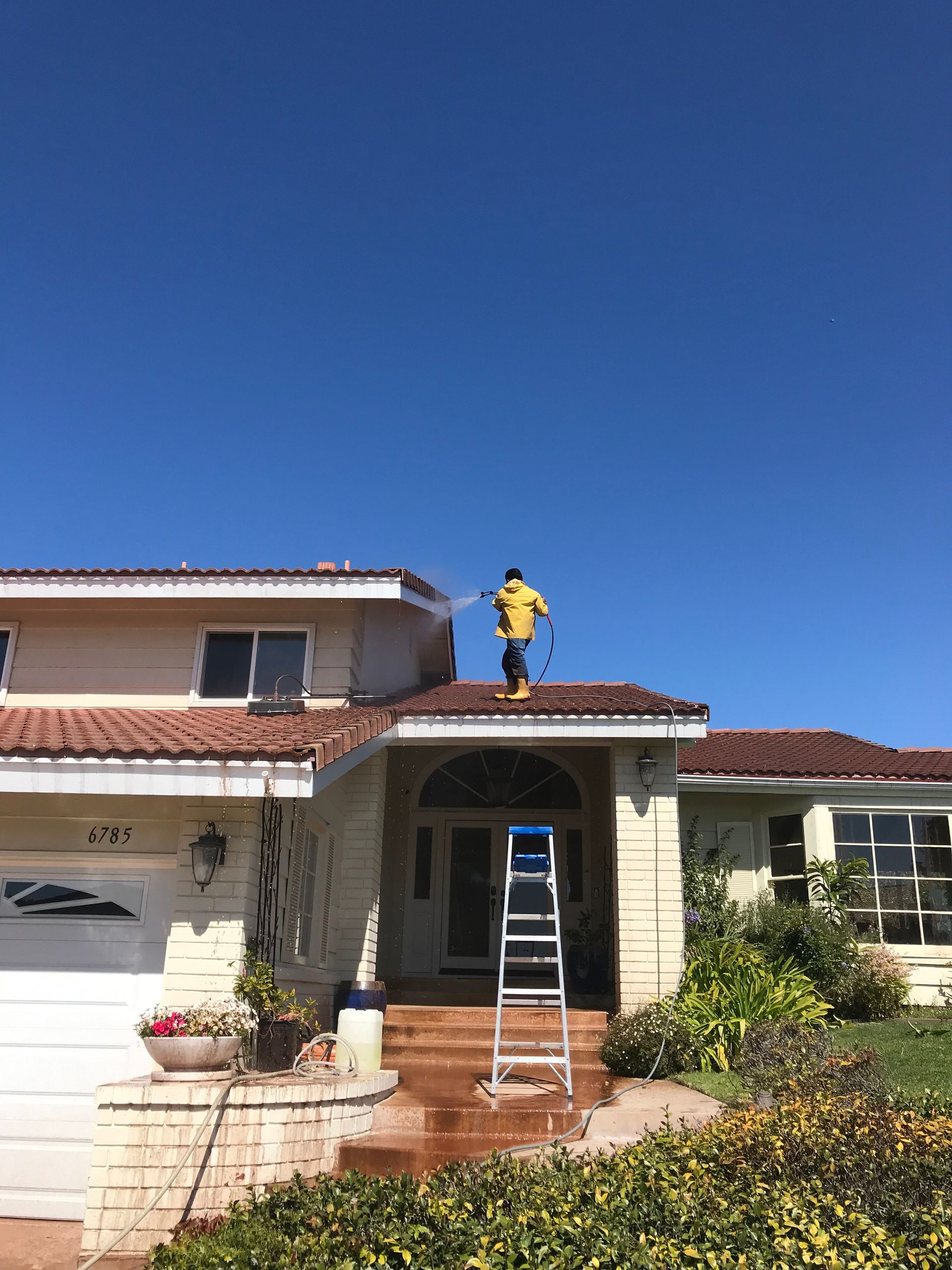 a man is cleaning the roof of a house with a pressure washer