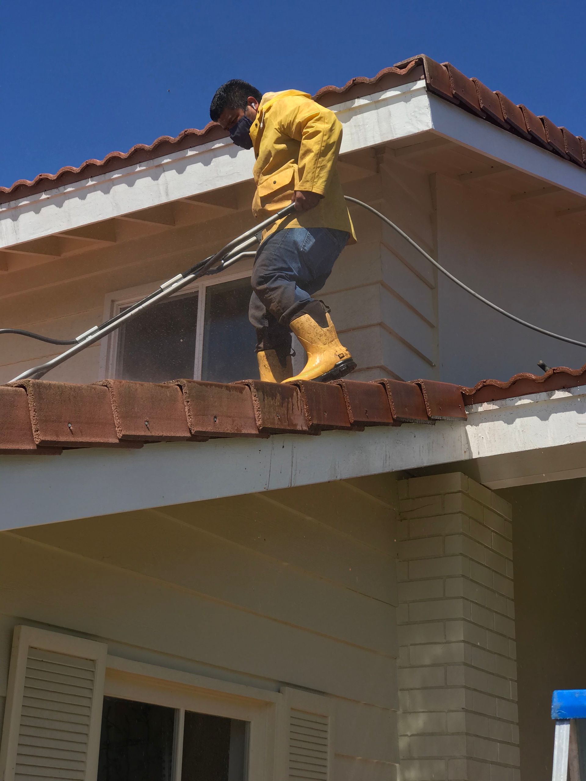 a man is cleaning the roof of a house with a hose