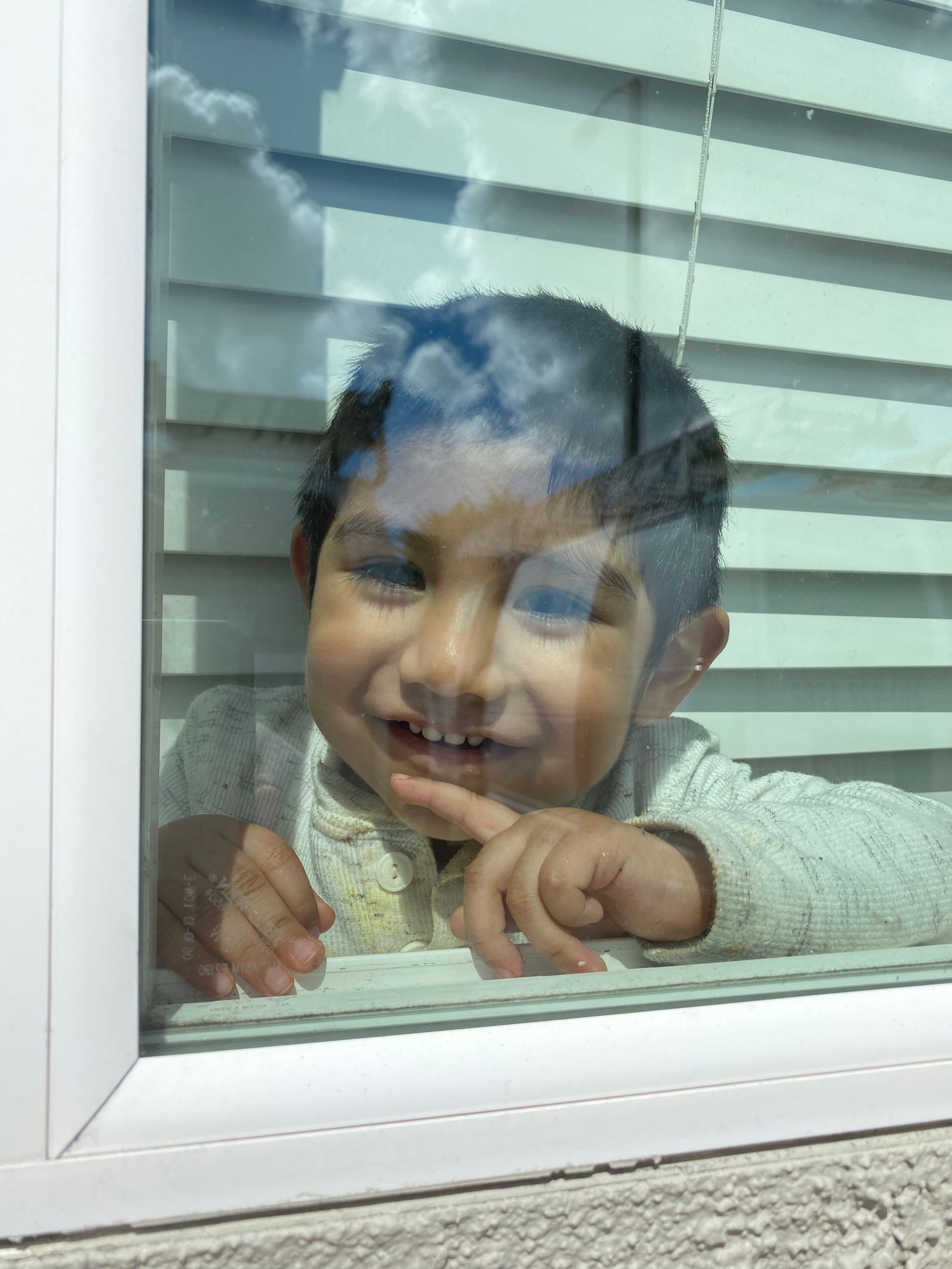 a young boy is looking out of a window and smiling